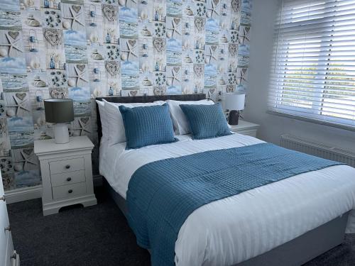 um quarto com uma cama grande com lençóis azuis e brancos em Oyster Retreat em Amble