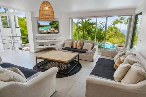 a living room with couches and a table at 7 bedrooms Villa, Nestled in the heights of Anse Marcel, one of the most discreet bays of the island. in Saint Martin