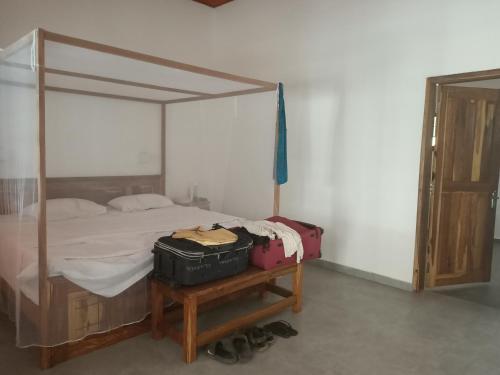 a bedroom with a canopy bed with luggage on a table at Casa Lamar in Sanyang