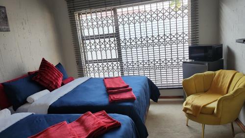 a bedroom with a bed and a chair and a window at Lerato's in Vanderbijlpark