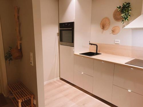 een keuken met witte kasten en een zwarte magnetron bij Cute little appartment in Kristiansand