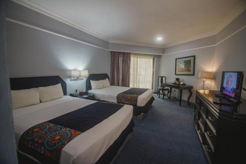 ein Hotelzimmer mit 2 Betten und einem TV in der Unterkunft Nk Hotel Nekié Tepic in Tepic