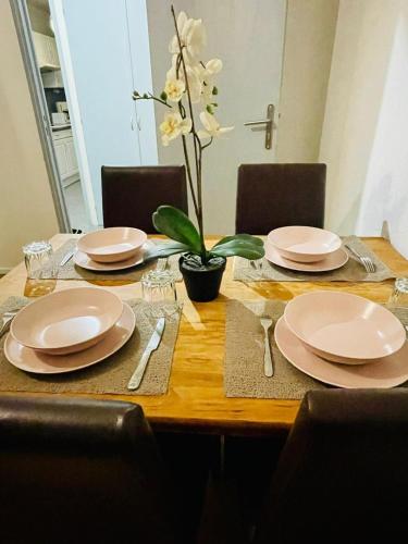 une table en bois avec des assiettes et des ustensiles dessus dans l'établissement 50 m2 dans un cadre calme et vert, à Franconville