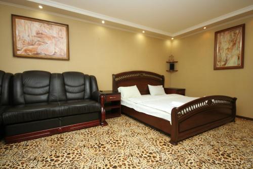 a bedroom with a bed and a leather couch at Pechersk Apartment in Kiev Center in Kyiv