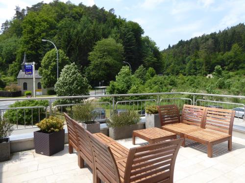 d'une terrasse avec 2 bancs en bois et une table. dans l'établissement Appart-Hotel Gwendy, à Bour