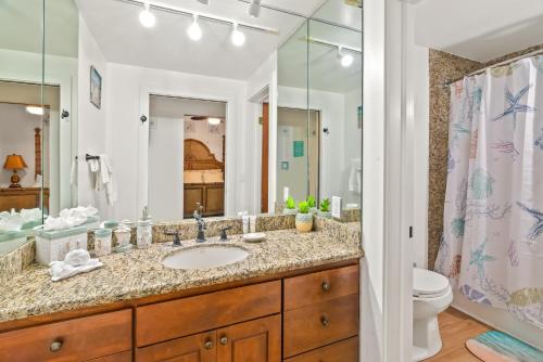 a bathroom with a sink and a toilet and a mirror at Kiahuna Paradise at Poipu beach, newly remodeled in Koloa