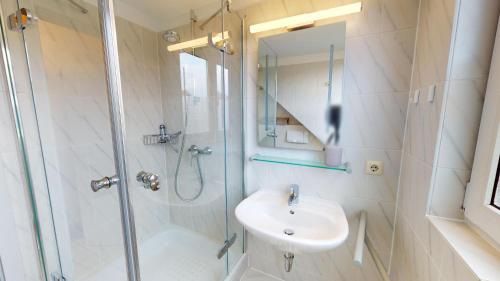 uma casa de banho com um chuveiro, um lavatório e um espelho. em Deich-Residenz App. 6 em Grömitz