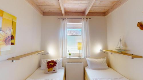 ペルツァーハケンにあるFeriendorf Südstrand Haus 17の白いベッド2台と窓が備わる客室です。