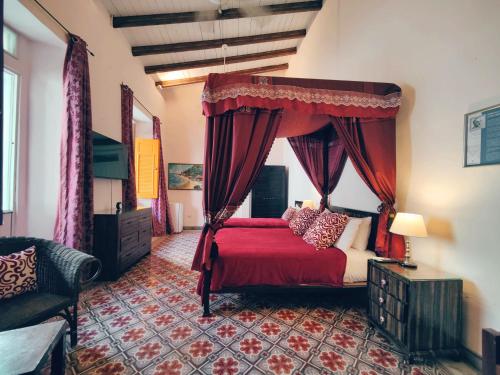 a bedroom with a red bed with a canopy at Casa Sánchez Hotel in Santo Domingo