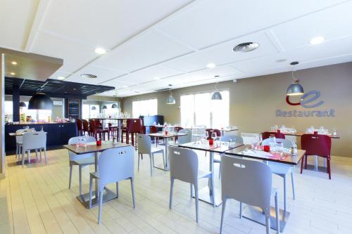 un restaurant avec des tables et des chaises et un panneau de restaurant dans l'établissement Campanile Béziers A9/A75, à Béziers