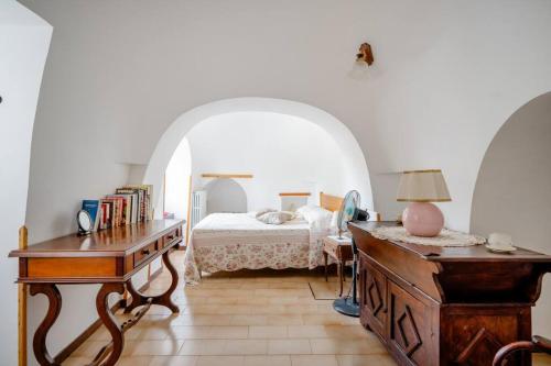 Schlafzimmer mit einem Bett und einem Tisch mit einem Schreibtisch sidx sidx sidx in der Unterkunft Trullo Rosy in Martina Franca