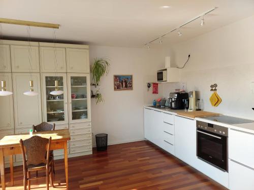 レーゲンスブルクにある146 Casafanteの白いキャビネットと木製テーブル付きのキッチン