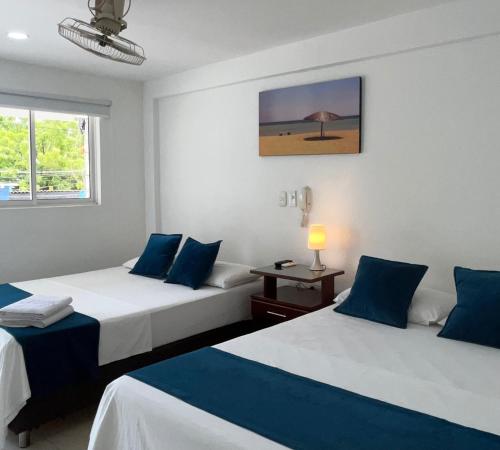 Habitación con 2 camas y sábanas azules y blancas. en Hotel Tucuraca by DOT Tradition, en Santa Marta