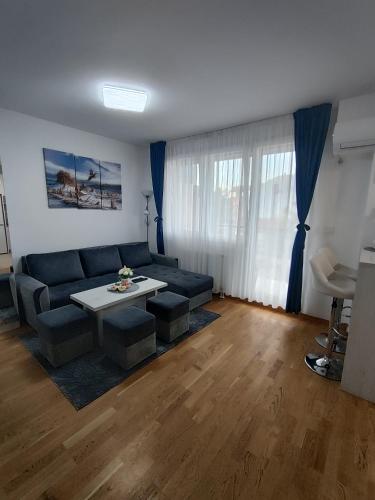 een woonkamer met een bank en een tafel bij Apartman LUXNS Novi Sad in Pasuljište
