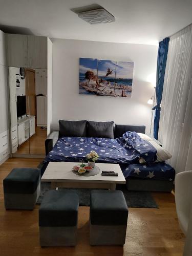 een woonkamer met een bed en een tafel bij Apartman LUXNS Novi Sad in Pasuljište