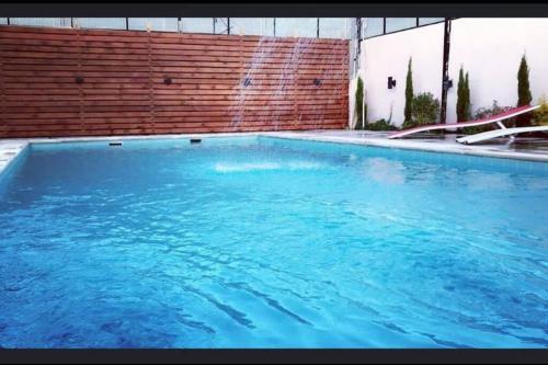 a swimming pool with blue water in front of a brick wall at Cozy Farm in Amman