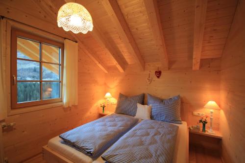 Schlafzimmer mit einem Bett, einem Fenster und einem Kronleuchter in der Unterkunft Feriendorf Walserland in Damüls