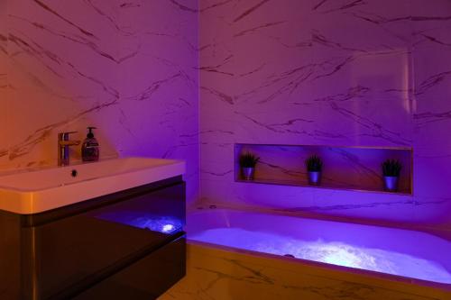 a bathroom with a tub with purple lighting at Bonneville House, Private Jacuzzi and Modern Interior in London