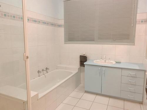 a white bathroom with a tub and a sink at The peaceful retreat in Mulgrave
