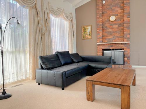 a living room with a black leather couch and a table at The peaceful retreat in Mulgrave