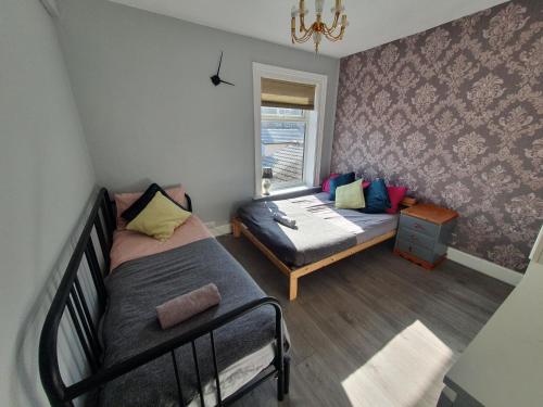 Habitación pequeña con 2 camas y ventana en Victorian Home, 3BR, Airport, M1, 6 beds, sleeps 12, en Luton