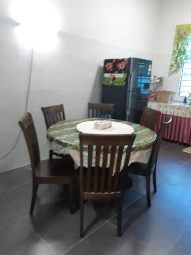 a table and chairs with a table and a refrigerator at JHC Homestay Puncak in Kampung Bota Kiri