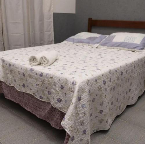 a bed with a white blanket and two towels on it at Pousada Gê in Caldas Novas