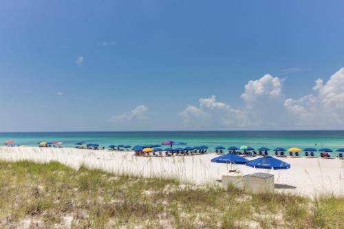 a beach with umbrellas and chairs and the ocean at Navarre Towers 602 in Navarre