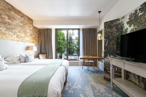 a hotel room with a large bed and a flat screen tv at Oude Werf Hotel in Stellenbosch