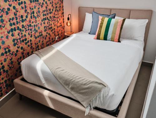 a bed with white sheets and pillows in a room at La Calma Poshtel in San Juan