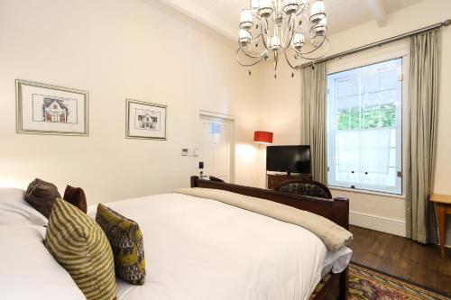 a bedroom with a large white bed and a window at Oude Werf Hotel in Stellenbosch
