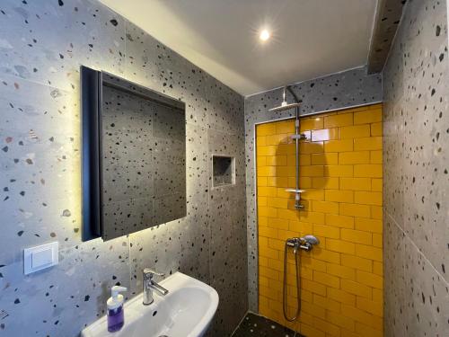 a bathroom with a sink and a shower with yellow tiles at Cabbana Hotel Lara in Antalya