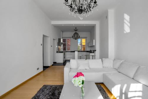a living room with a white couch and a vase of flowers on a table at Warsaw Castle Apartments - Prime Location, Historic City Center, Castle View, Fast Internet - by Rentujemy in Warsaw