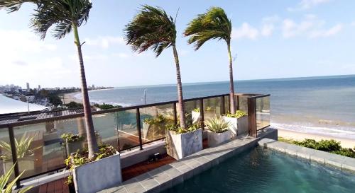 a swimming pool with palm trees and the ocean at Arpoar Suítes 330 in João Pessoa