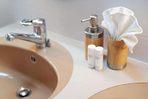 a sink with a faucet and two bottles of soap at la belle vue Boutique Hotel & Café in Spiez