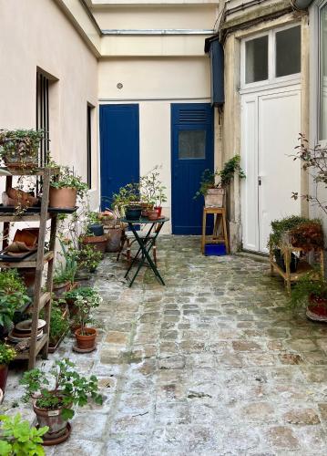 une cour avec des plantes en pot et une porte bleue dans l'établissement Maison de ville cosy Canal Saint Martin, à Paris