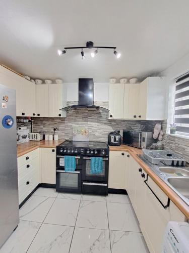 a kitchen with white cabinets and a black stove top oven at Professional Stay Doctors Nurses Trades in Luton