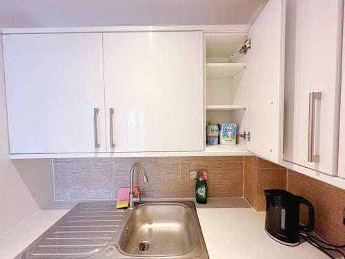 uma cozinha com um lavatório e armários brancos em 1 Bed Room Flat Near Central em Londres