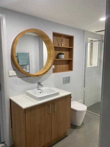 a bathroom with a sink and a toilet and a mirror at Merimbula Lake Apartments in Merimbula