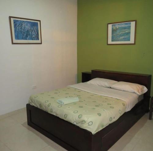 1 cama en un dormitorio con 2 cuadros en la pared en Hostal Belén en Popayán