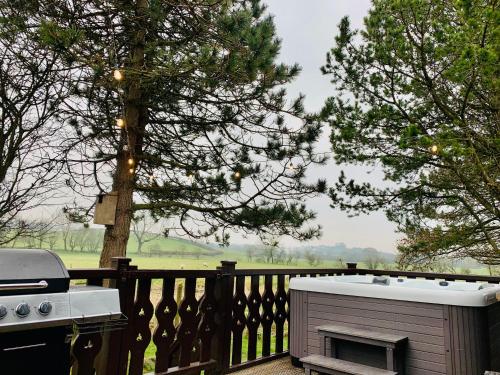 una vasca idromassaggio seduta su una terrazza accanto a una griglia di Keer Side Lodge, Luxury lodge with private hot tub at Pine Lake Resort a Carnforth