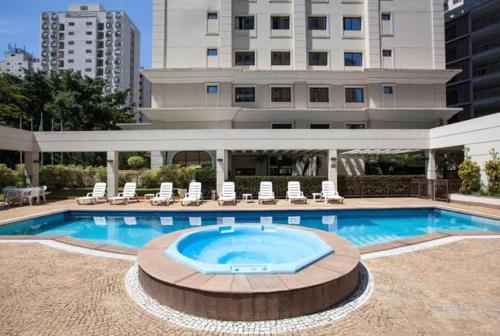 a large swimming pool with chairs and a building at Executivo em Hotel - Vila Olímpia in Sao Paulo