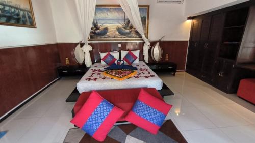 a bedroom with a large bed with red and blue pillows at Baruna Sari Villa in Ubud