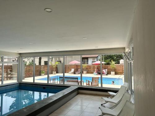 an indoor swimming pool with chairs and a swimming pool at Suite del sol 121 in Pinamar