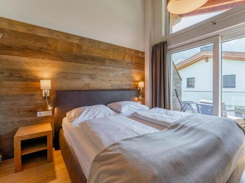 1 dormitorio con 1 cama grande y pared de madera en Chalet Lengberg B1, en Niedernsill