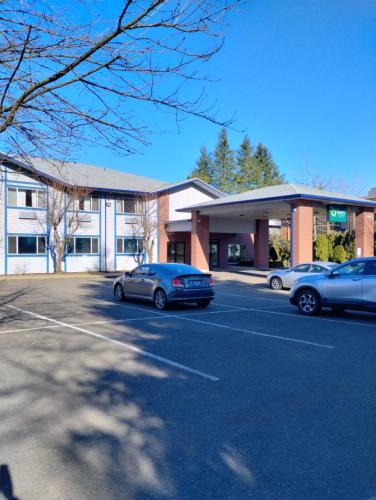 zwei Autos auf einem Parkplatz vor einem Gebäude geparkt in der Unterkunft Quality Inn & Suites Wilsonville in Wilsonville