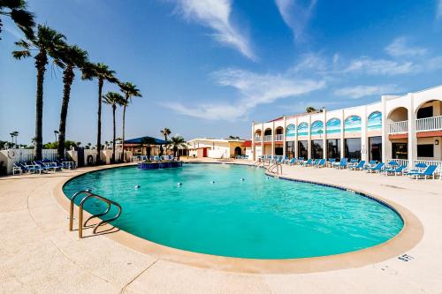 a swimming pool at a resort with chairs and palm trees at Long Island Village 502 Clam in Port Isabel