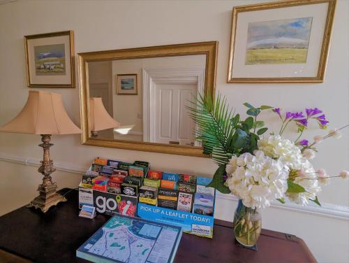 une table avec un vase de fleurs et un miroir dans l'établissement The Senarth, à Llandudno