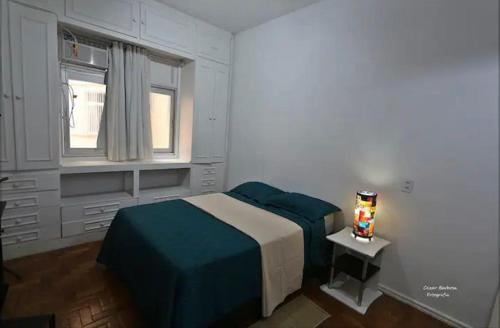 een witte slaapkamer met een bed en een raam bij Cantinho Carioca Apto em Copacabana in Rio de Janeiro