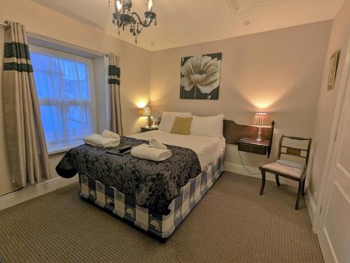 una camera da letto con un letto, una sedia e una finestra di The Senarth Guesthouse - Seaside Guesthouse with Breakfast & Free Parking a Llandudno